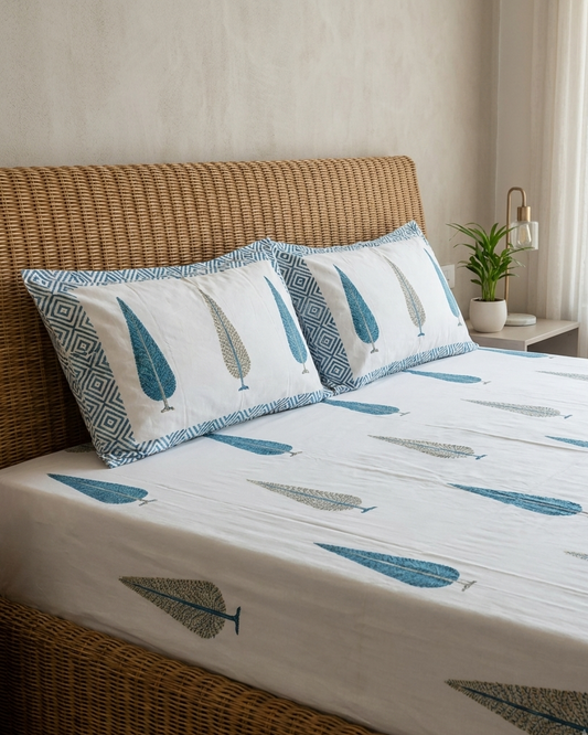 Close-up of Mallika Arka Luxe Cotton bedsheet showcasing blue and olive leaf motifs on a crisp white background