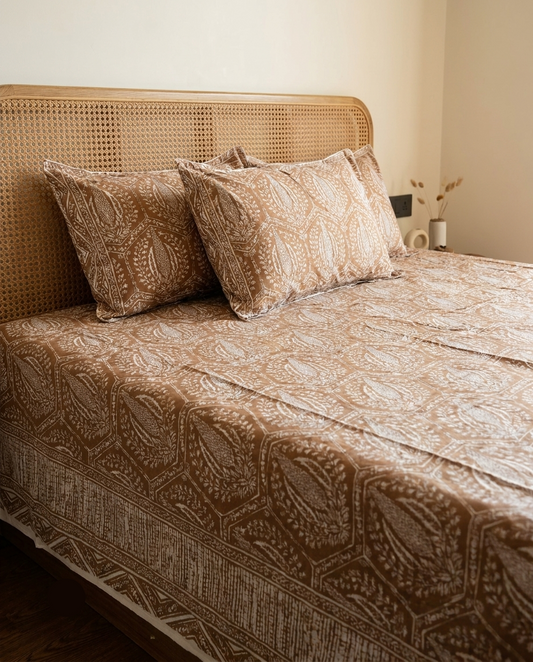 Bed with patterned cover and pillows against a beige wall