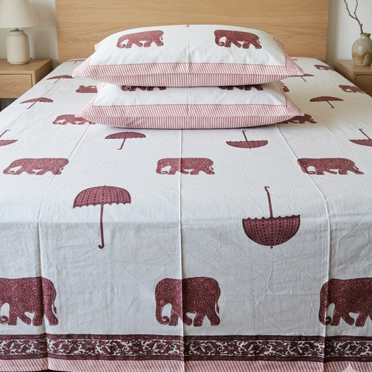 Bed with red elephant and umbrella patterned bedding in a bedroom setting.