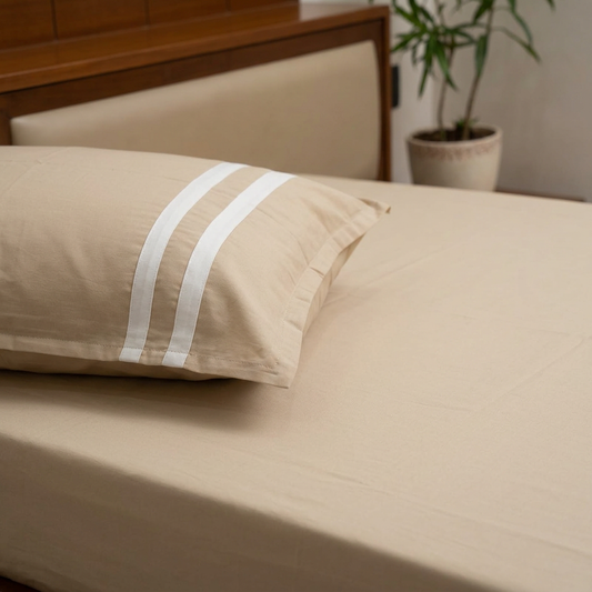 Cream bedsheet and striped pillow detail close-up without a top sheet